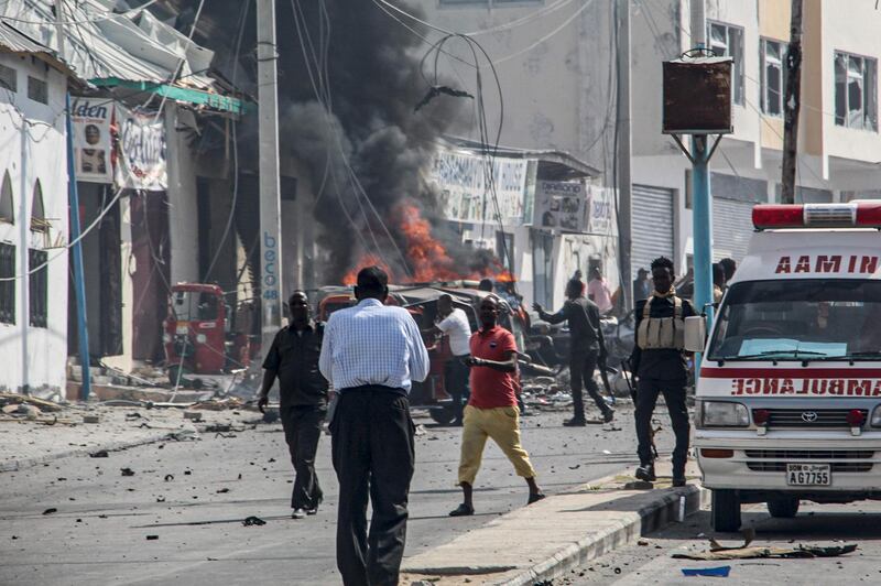 Security officers stand around the site of a car bombing attack near a security checkpoint in Mogadishu, Somalia, on February 13, 2021.  At least three people were killed and eight others wounded after a car bomb detonated near a security checkpoint along a key road in Mogadishu, security official and witnesses said. / AFP / STRINGER
