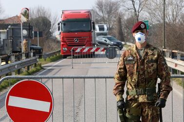 An Italian Army officer wearing a protective face mask stands at a roadblock at the entrance to the small town of Vo' Euganeo, near Padova, northern Italy. Italian authorities announced on Monday that there are over 200 confirmed cases of coronavirus in the country, with at least five deaths. EPA