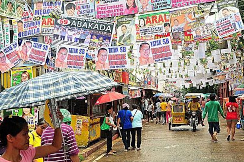 Filipinos walk under election campaign posters as the Philippines goes to the polls this morning. Veejay Villafranca / Getty Images