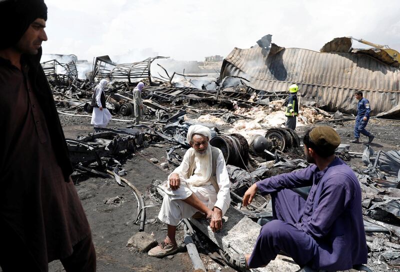 Truck owner Dad Mohammad, 78, centre, sits among the wreckage of fuel tankers and trucks, following an overnight fire on the outskirts of Kabul, Afghanistan. Reuters