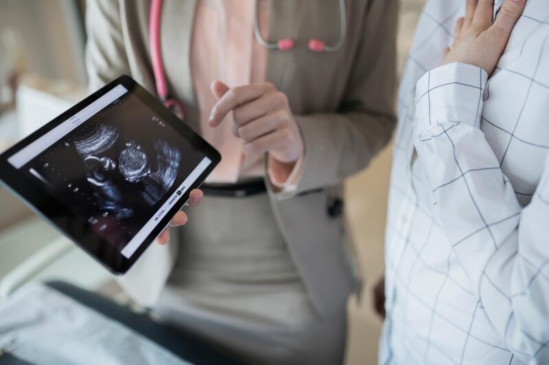 Obstetrician showing pregnant patient ultrasound on digital tablet