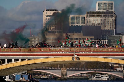 Protesters wave flags and hold flares during a pro-Palestinian protest in London. AP 