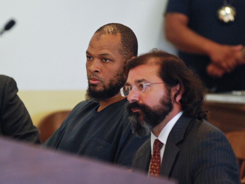 Siraj Ibn Wahhaj, left, sits next to public defense attorney Aleks Kostich at a first appearance in New Mexico state district court in Taos, N.M., Wednesday, Aug. 8, 2018, on accusations of child abuse and abducting his son from the boy's mother. Authorities were waiting to learn if human remains found at a disheveled living compound were those of Wahhaj's missing son. Authorities also allege Wahhaj was conducting weapons training with assault rifles at the compound near the Colorado border where they say they found 11 hungry children living in filthy conditions in a raid Friday. (AP Photo/Morgan Lee)