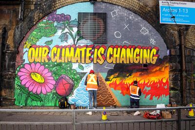 Street artists paint a mural on a wall opposite the Cop26 climate summit venue in Glasgow last week. AFP