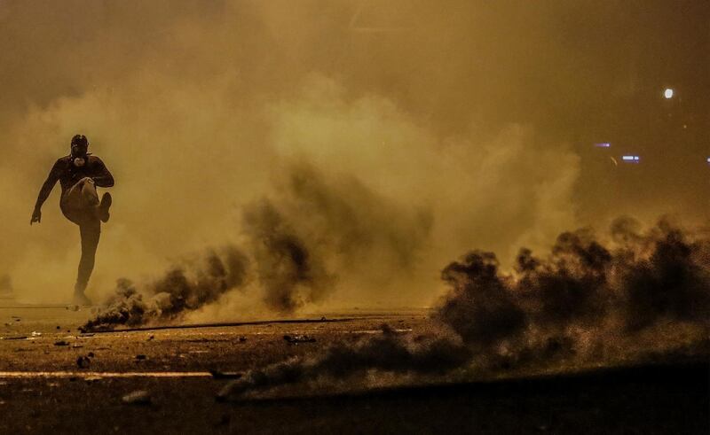 A protesters kicks a tear gas grenades back at riot police during clashes in central Beirut.  EPA