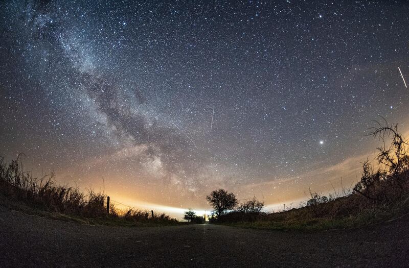 The milky way and traces of meteors illuminate the sky over Burg on the Baltic Sea island of Fehmarn, northern Germany. Daniel Reinhardt / dpa via AP.