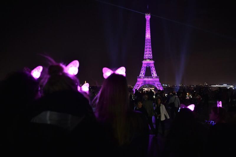 Tourists pose in front of the illuminated Eiffel Tower during an event to mark the Breast Cancer Awareness month in October in Paris. AFP