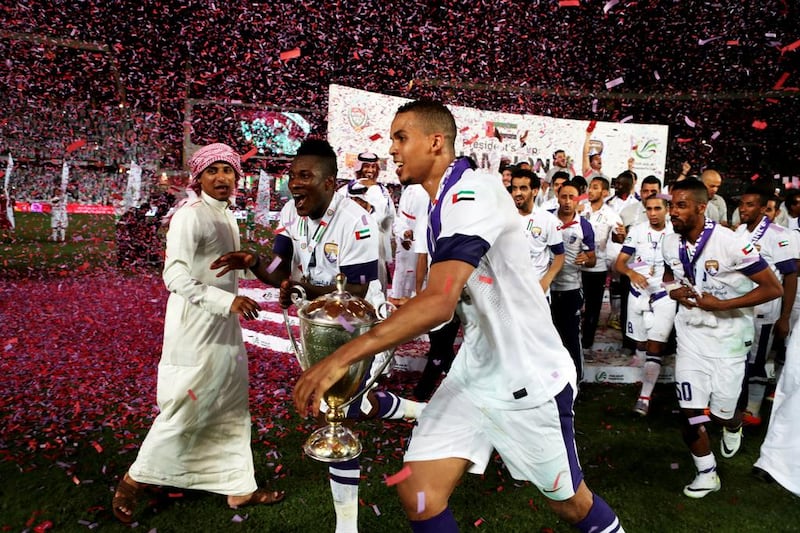 Al Ain’s Asamoah Gyan, left, and Ismail Ahmed, centre, run with the President’s Cup after defeating Al Ahli at Zayed Sports City in Abu Dhabi on Sunday night. Christopher Pike / The National



