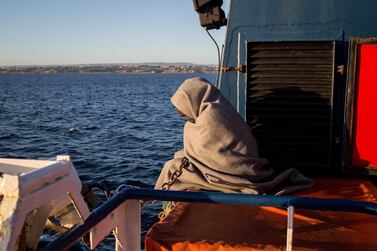 A migrant wrapped in a blanked waits on the deck of the Sea Watch 3 NGO vessel on January 31, 2019 off southeastern Sicily coats, as the ship sails towards Catania to disembark the 47 migrants onboard. - 47 rescued migrants aboard the Sea Watch NGO vessel were expected to disembark in Catania after Italy and France, Germany, Malta, Portugal, Romania and Luxembourg agreed to take them in. The fate of the migrants has been at the centre of a standoff between Italy's far-right Deputy Prime Minister Matteo Salvini -- who has closed the ports to migrants and demanded Europe take its share -- and the German NGO Sea Watch. (Photo by FEDERICO SCOPPA / AFP)