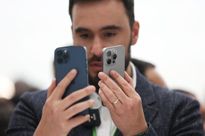 A man compares the Apple iPhone 15 Pro and iPhone 15 Pro Max phones at the event. Getty Images / AFP