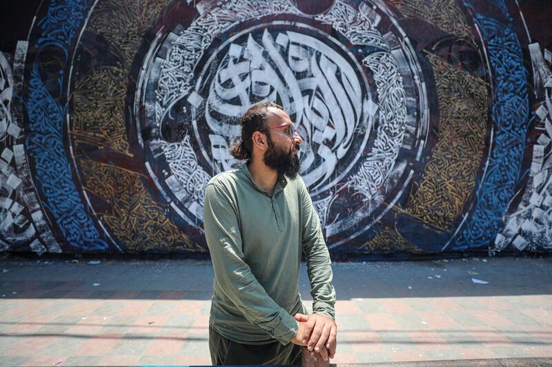 Bilal Khaled in front of an example of his graffiti on a wall at Alazhar University in Gaza City. All photos: Nagham Mohanna for The National