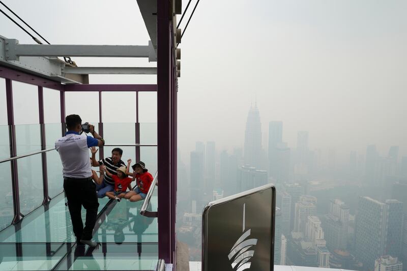 Tourists take a picture from the Skybox in Kuala Lumpur Tower as the Malaysian capital is shrouded in haze caused by the fires in Indonesia. AP Photo