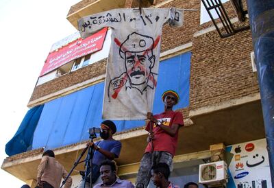 Sudanese anti-military demonstrators raise a banner bearing a crossed-out image of Gen Abdel Fattah Al Burhan, who seized power in a coup 13 months ago. AFP