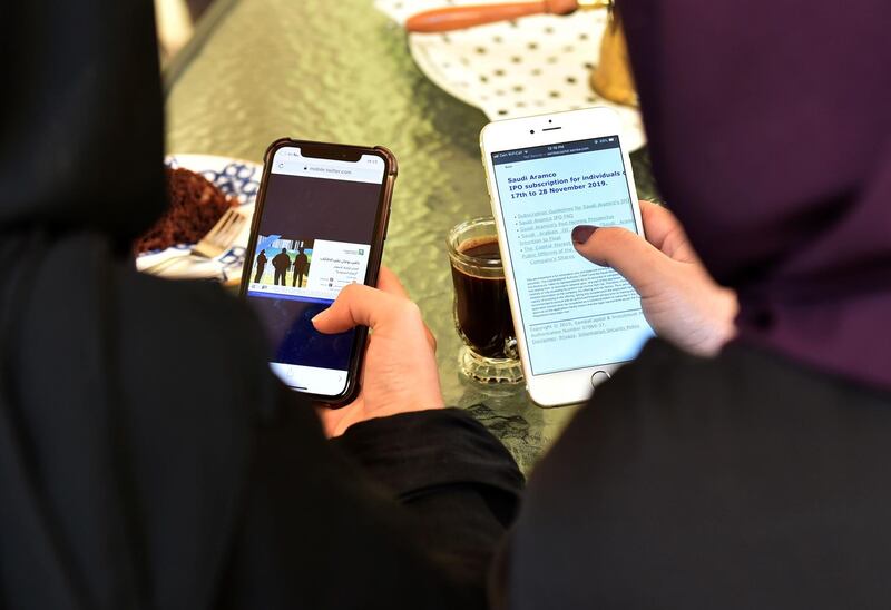 A picture taken on November 27, 2019 shows women in Saudi Arabia's capital Riyadh checking on their mobile phones an announcement on Saudi Aramco's public offering on an investment services website. Saudi Aramco announced earlier this month that it has decided to sell up to 0.5 percent of its shares to individual investors while it will decide on the percentage for larger investors later its much-anticipated initial public offering. Aramco's much-anticipated initial public offering began on November 17, to end on November 28 for individual investors and on December 4 for institutional investors, with a final share price to be determined a day after subscriptions close. / AFP / FAYEZ NURELDINE
