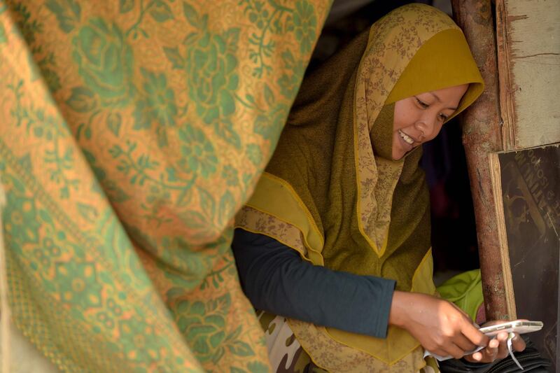 A Cambodian-Muslim woman checks her smartphone at her home on the Mekong river in Phnom Penh.Tang Chhin Sothy  / AFP Photo