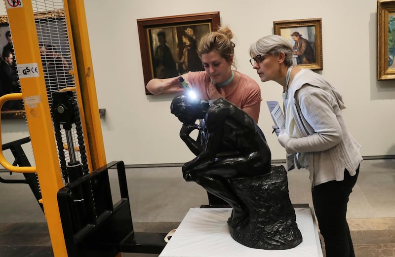 Staff members examine Rodin's 'The Thinker' bronze statue after it was unpacked to install it at the Louvre Museum in Abu Dhabi. Kamran Jebreili / AP photo
