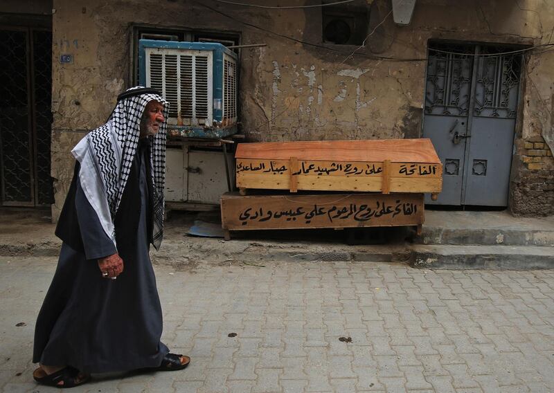 An Iraqi man walks past empty coffins in the Washash district, in western Baghdad.   AFP