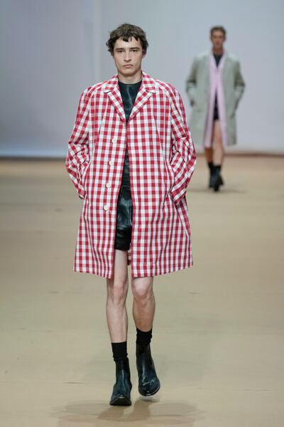 Gingham men's coats layered over gaberdine jackets and black leather shorts, as part of the Prada men's spring/summer 2023 collection presented in Milan, Italy. Photo: EPA