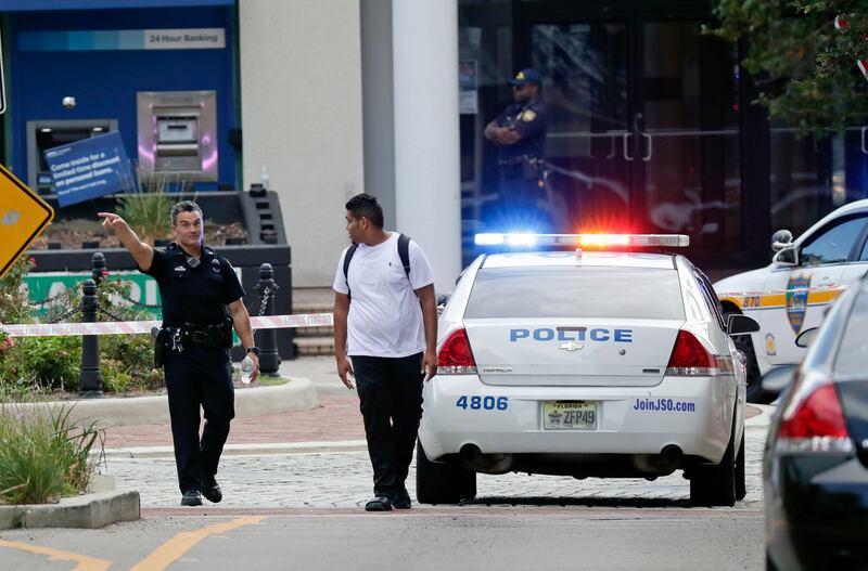 A police officer directs a pedestrian away from a blocked off area near the scene of a mass shooting at Jacksonville Landing. AP Photo