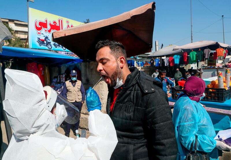 A health worker collects a saliva sample from a man for a PCR coronavirus test at the Shurja market, in Baghdad, Iraq. AP Photo