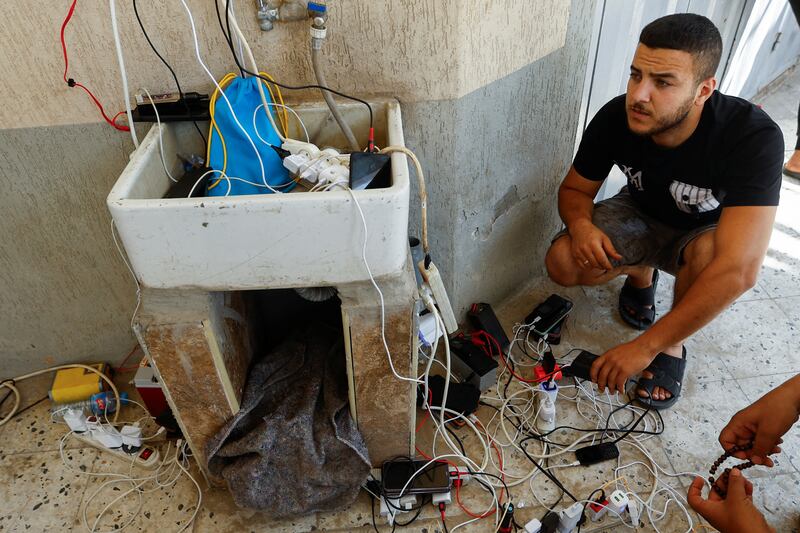Palestinians charge their phones using solar power as electricity supplies remain cut off in Khan Younis, southern Gaza. Reuters