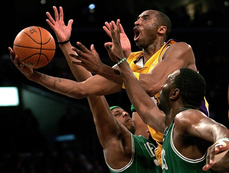 Los Angeles Lakers' Kobe Bryant, top, goes up for a shot between the Boston Celtics' Paul Pierce, left, and Al Jefferson during the first half of an NBA basketball game in Los Angeles. AP Photo/Branimir Kvartuc