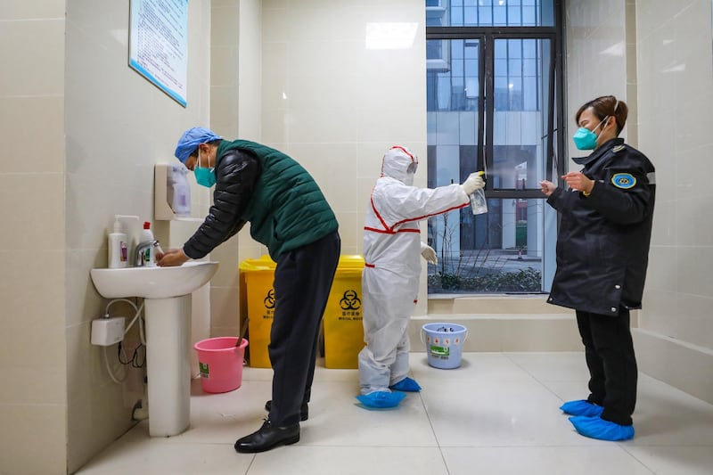A fully protected worker disinfects the ambulance staff at the emergency center in Wuhan, Hubei province, China.  EPA