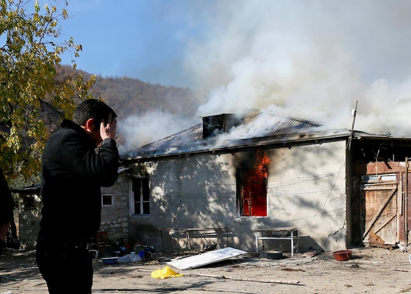 A man reacts as he stands near a house set on fire by departing Ethnic Armenians, in an area which is soon to be turned over to Azerbaijan, in the village of Cherektar.  Reuters