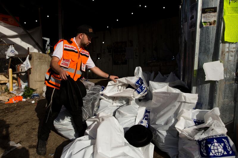 A rescue worker collects hats worn by of Orthodox Jews in plastic bags after dozens were killed in crush at religious festival in Mount Meron. Getty Images