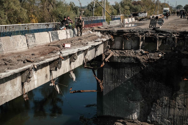 Residents try to cross a destroyed bridge in the Kharkiv region of Ukraine. AFP