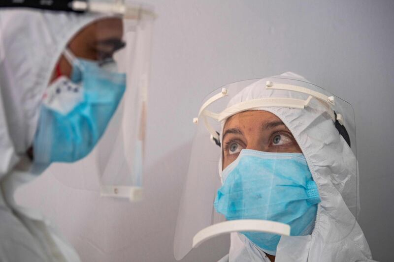 Health officer wearing protective clothing speak as they prepare before travelling to collect swab samples from confined people who are believed to have been in contact with coronavirus patients. AFP