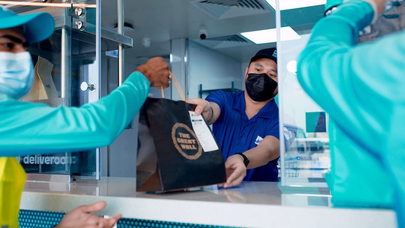 A Deliveroo rider collects a meal for home delivery at the company's new dark kitchen in Dubai. Courtesy: Deliveroo