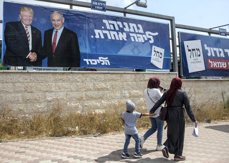 Arab woman with a child pass by an  giant election campaign billboard of the ruling Likud party showing Israeli Prime Minister Benjamin Netanyahu shaking hands with US President Donald J. Trump in Jerusalem, September 8 ,2019. 
(Photo by Heidi Levine for The National).