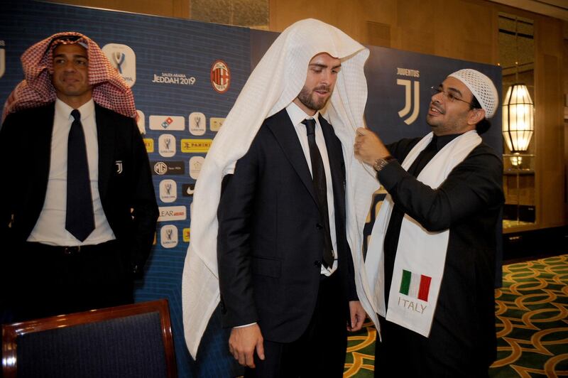 Miralem Pjanic gets shown how to don the ghutra. Photo: Getty