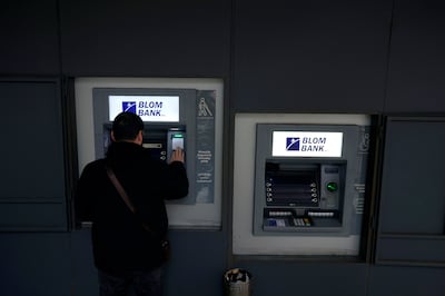 A man uses an ATM outside a closed bank in Beirut. AP