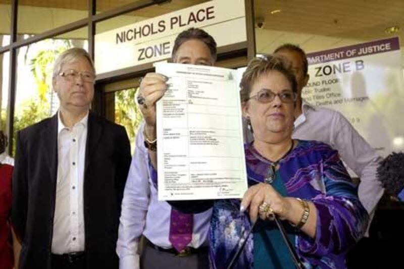 Lindy Chamberlain-Creighton (R) shows off daughter's Azaria's death certificate as ex-husband Michael Chamberlain (L) looks on after a coroner ruled that a dingo snatched baby Azaria Chamberlain.