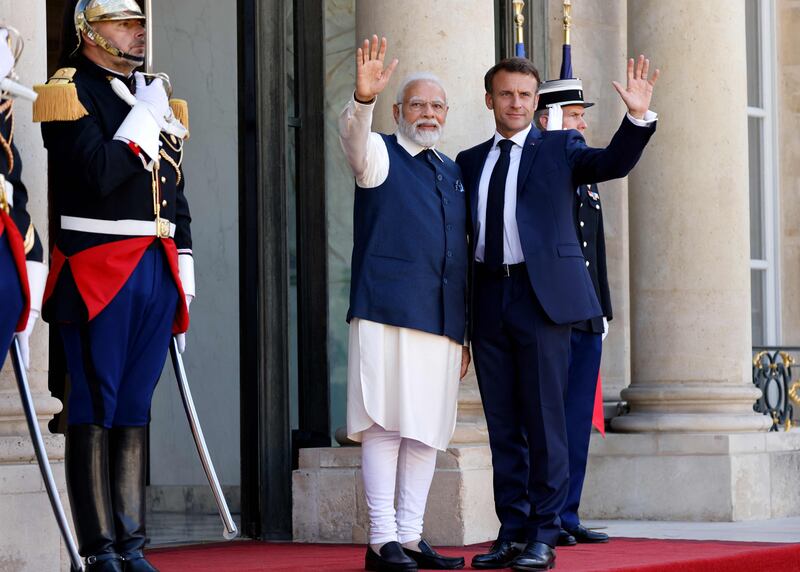 Mr Macron and Mr Modi wave to the press before a meeting. AFP