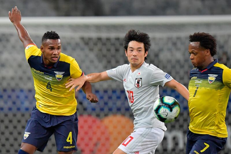 Japan's Shoya Nakajima, centre, vies for the ball with Ecuador's Pedro Pablo Velasco. AFP