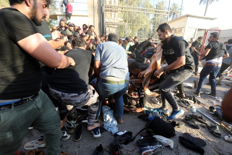 Supporters of Mr Al Sadr assist protesters injured during clashes with security forces near the prime minister's office in Baghdad. EPA