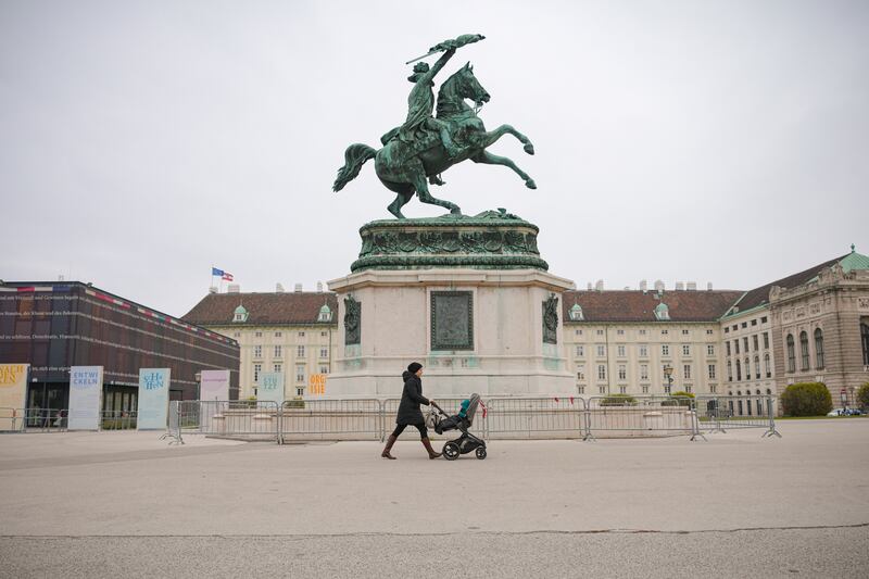 A pedestrian and child pass a statue of Archduke Karl in the Heldenplatz, Vienna, on Monday, the first day of Austria's 20-day coronavirus lockdown. AP