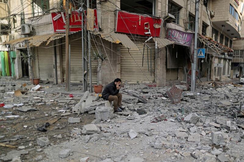 A Palestinian man sits on debris outside a building that was damaged in Israeli air strikes, in Gaza City. Reuters