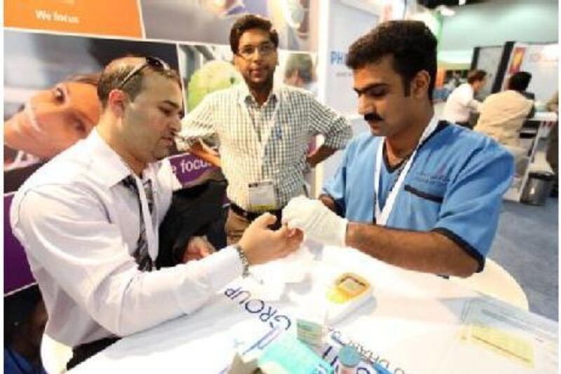 Mohamad Halas, left, has his cholesterol level checked by Riyas Kizhakkayil Meethel, a registered nurse with Lifeline Hospital, free of charge at the Abu Dhabi Medical Congress yesterday.