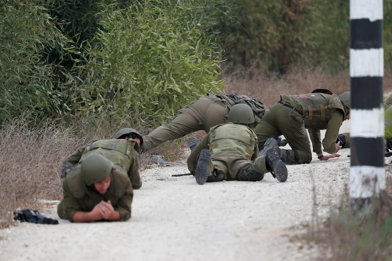 Israeli soldiers take cover during a missile attack next to the border with Gaza, near Sderot, southern Israel. EPA