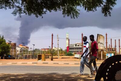 An otherwise normal street in Khartoum on Thursday apart from the smoke rising from a battle behind buildings in the background. AFP