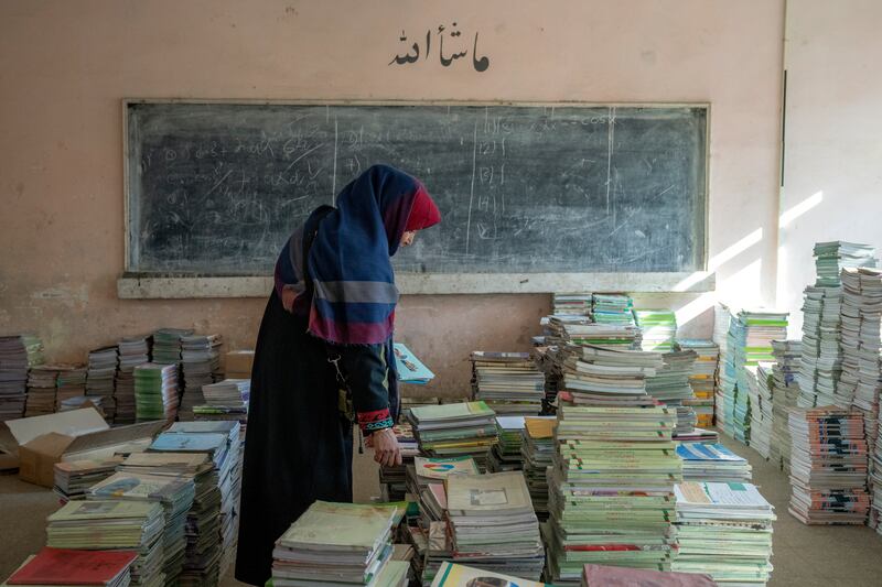 Amanah Nashenas, 45-year-old an Afghan teacher, collects books in a school in Kabul, Afghanistan, on December 22. AP