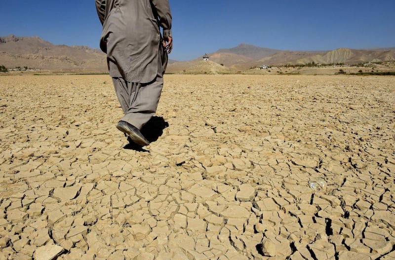TOPSHOT - In this picture taken on October 6, 2018, a Pakistani villager walks on the cracks of the dry Hanna lake in Urak Valley, some 15 km from Quetta. The Hanna lake provided water to local people and to the surrounding natural habitat. Balochistan has been facing long dry spells which may force the local population to migrate to eastern Balochistan. Some half million people are displaced due to severe drought caused by no rain or less rain. / AFP / BANARAS KHAN
