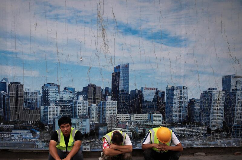 Chinese workers take a break outside a construction site wall depicting the skyline of the Chinese capital at the Central Business District in Beijing, Tuesday, June 26, 2018. Chinese regulators have freed up an extra $100 billion for bank lending in a move financial analysts said could help to reassure investors amid trade tensions with Washington. The reduction on Sunday, June 24, 2018 in reserves banks are required to hold was part of a series of such cuts economists had forecast before the dispute with President Donald Trump erupted. But they said the announcement could help to defuse fears a threatened U.S. tariff hike might dampen Chinese economic growth. (AP Photo/Andy Wong)