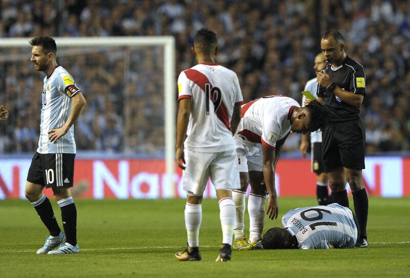 Brazilian referee Wilton Pereira Sampaio yellow cards Peru's Renato Tapia (2-R) as Argentina's Ever Banega lies on the ground during their 2018 World Cup qualifier football match in Buenos Aires on October 5, 2017. / AFP PHOTO / Alejandro PAGNI