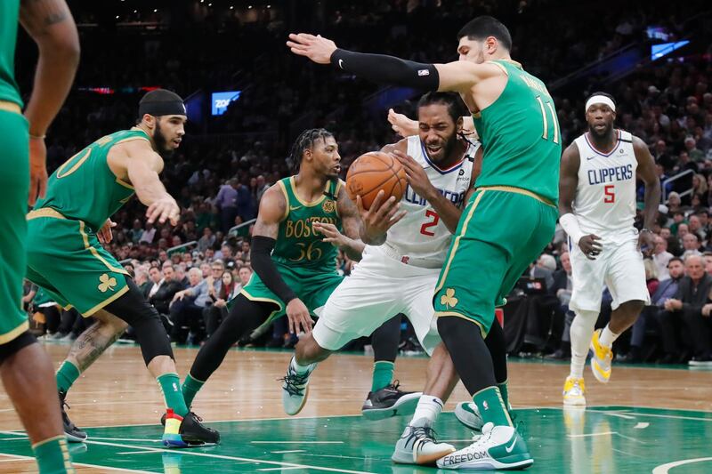 Los Angeles Clippers forward Kawhi Leonard, centre, tries to drive through the defense of Boston Celtics center Enes Kanter, right, during the second half of an NBA basketball game in Boston, USA. AP Photo