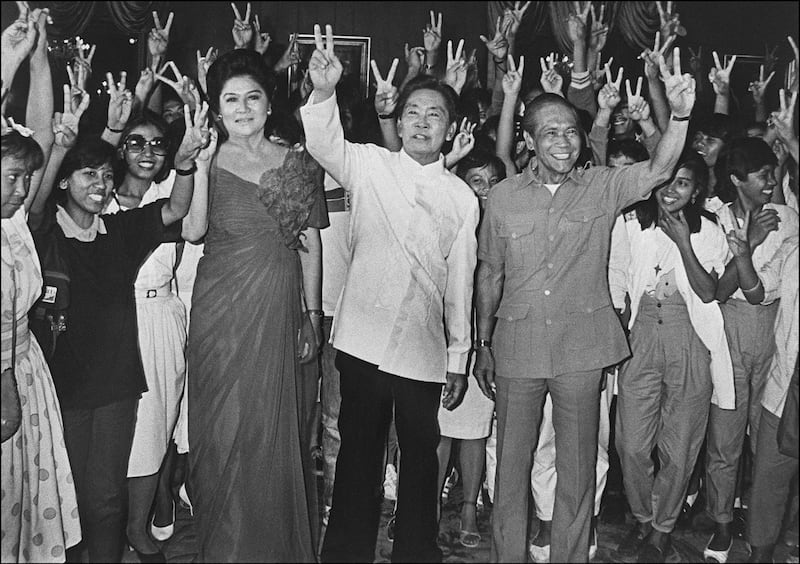 Surrounded by supporters, Philippines president Ferdinand Marcos, his wife Imelda and vice president Arturo Tolentino make the victory sign after winning presidential elections in Manila in 1986. AFP